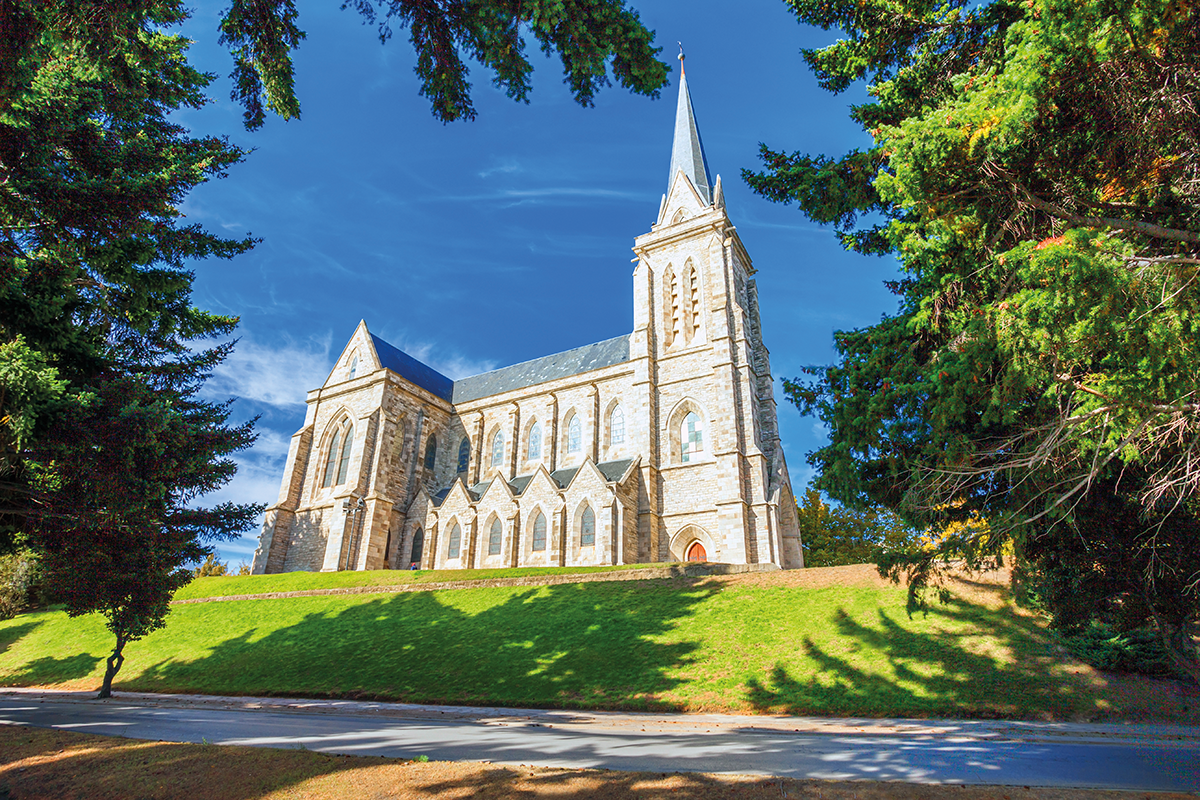 fachada de uma igreja com um gramado e árvores em volta