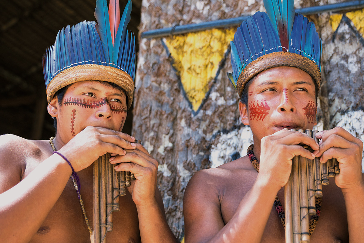Dois indígenas tocando flauta
