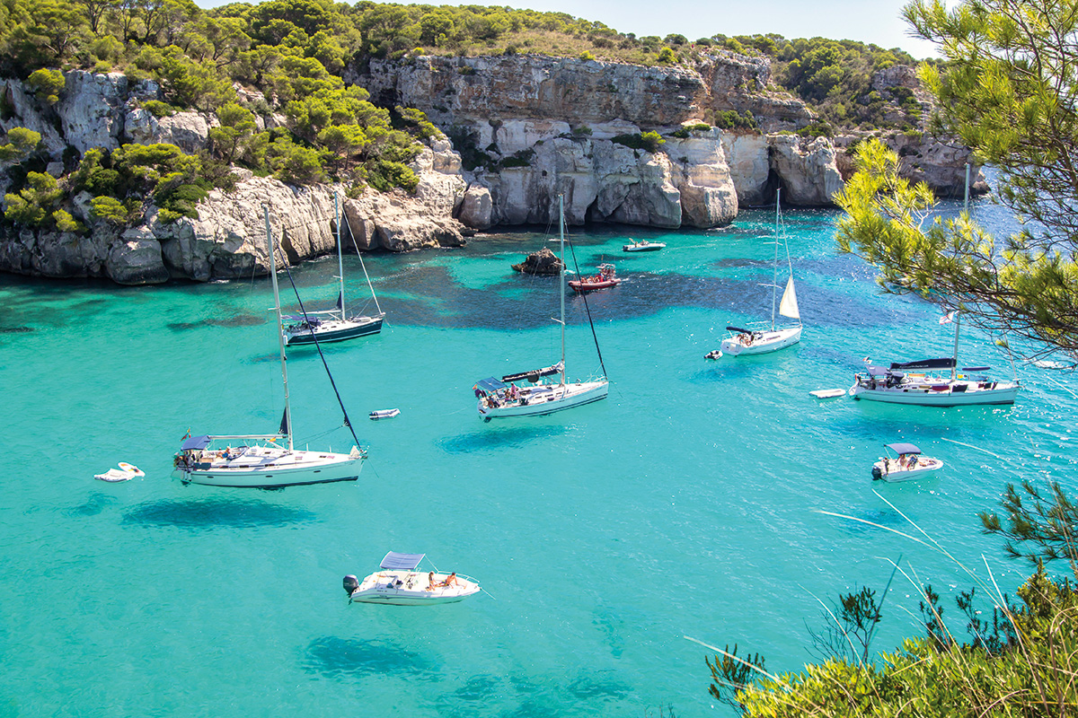 Várias embarcações espalhadas pelas águas cristalinas de Menorca