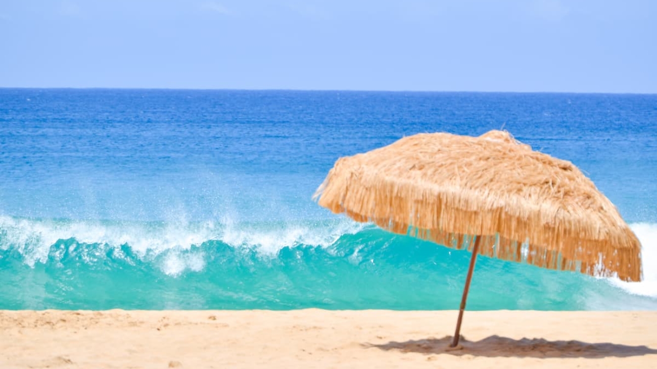 mar azul, areia e guarda-sol