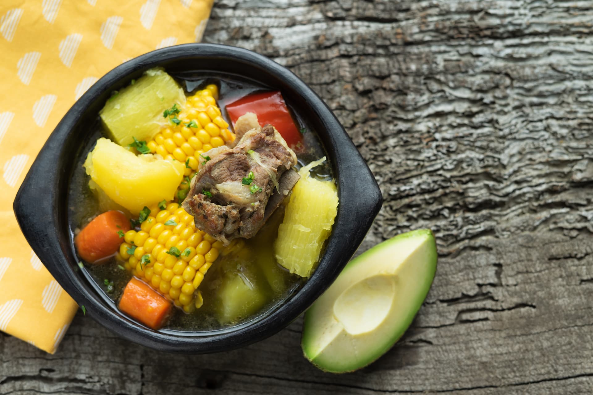 sancocho-comida-tipica-colombiana-em-uma-tigela-preta-sobre-um-fundo-de-madeira-rustica